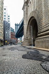 Fototapeta premium Manhattan Bridge towers in the background of Brooklyn street alley