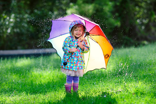 cute toddler girl wearing waterproof coat with colorful umbrella