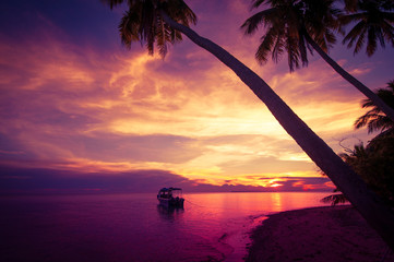 Tropical island in the sunset with a boat