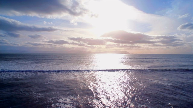 Beautiful drone footage of seascape against sky during sunset. Tracking shot of sunlight reflecting on serene ocean waves. Scenic view of seascape. HD 1080 video.