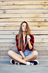 Trendy hipster girl sitting on the wooden porch