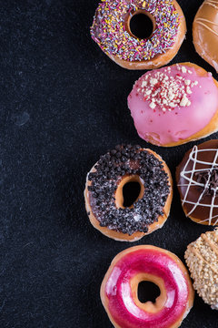 hand decorated donuts on black slate ,food border background,