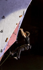 Obraz na płótnie Canvas Failed attempt. Male rock climber falling of the wall. Nigh spotlight blurred movement.