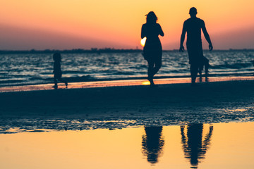 Family on a beach in summer at sunset