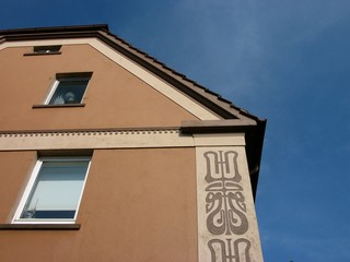 Ornamente an der braunen Fassade eines sanierten Altbau in Pastelltönen und Naturfarben vor blauem...