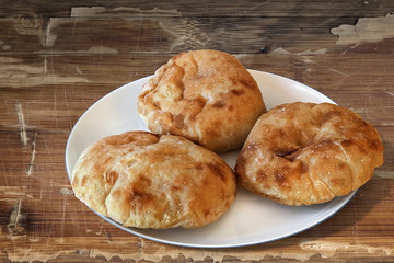 Plate with Pita Bread loafs and Baguette slices, on old Wood.