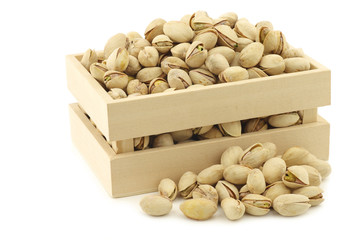 Pistachio nuts in a wooden box on a white background