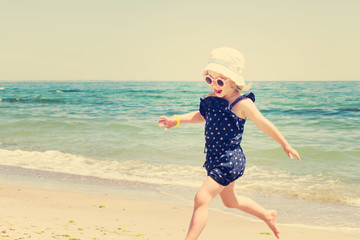 Little girl running and playing on the beach. The image is tinte