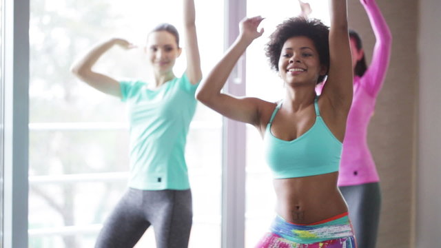 group of smiling people dancing in gym or studio