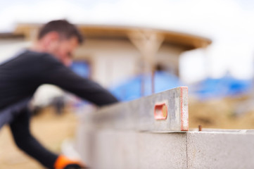 Bricklayer putting down another row of bricks in site