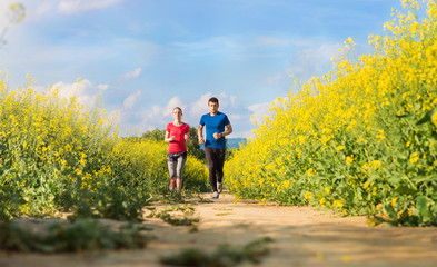 Obraz premium Beautiful young runners outside in canola field