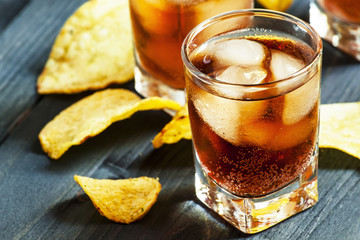 Cola with ice in glasses and chips, selective focus