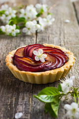 Tartlet with plum on wooden background