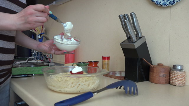 Female hands put white sauce on spaghetti pasta. 4K