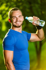 Athletic mature man drinking water from a bottle