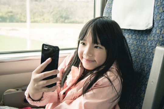 Little asian girl looking through window.