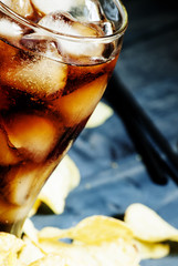 Potato chips and cola in a large glass, selective focus