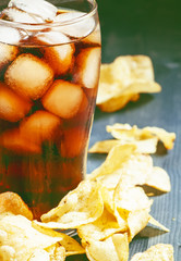 Potato chips and cola in a large glass, selective focus