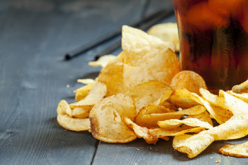 Potato chips and cola in a large glass, selective focus
