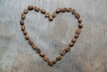 Heart of coffee beans on wooden background