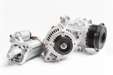 photos on the composition of the three parts for the engine. Generator, air conditioning compressor and the starter on a gray background