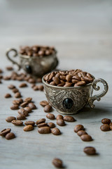 Coffee beans in arabian silver vintage cups on wooden background