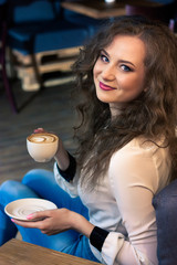 Smiling girl with coffee sitting in a chair