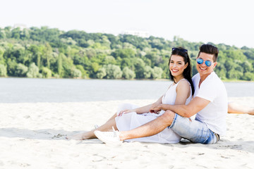 Naklejka na ściany i meble Romantic young couple sitting at a beach
