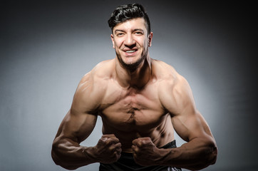 Muscular man posing in dark studio