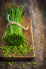 bunch of  chives on a wooden cutting board - obrazy, fototapety, plakaty