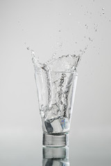 Splash com gelo caindo no copo de água