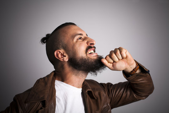 Hipster con cazadora de piel estir&aacute;ndose la barba