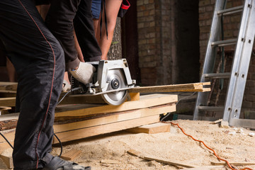 Men Using Power Saw to Cut Planks of Wood