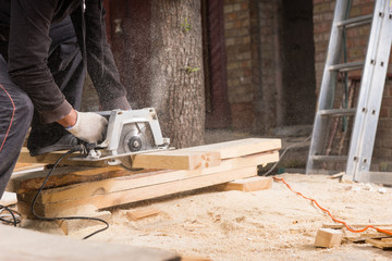 Man Using Power Saw to Cut Planks of Wood