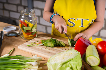 Young girl slicing a cucumber for bottling