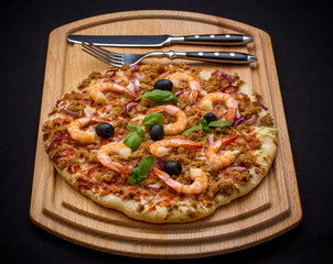 Tuna pizza with shrimp and black olives, cutlery