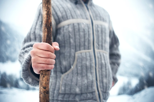 Man holding wood stick in the cold winter while snowing
