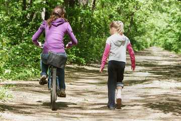 Obraz premium Mom and daughter on cycling in the forest.