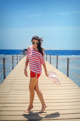 young woman full of energy on a pontoon in front of the sea on a sunny day