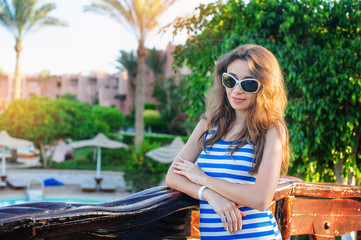 beautiful woman in a striped dress walks in the summer park