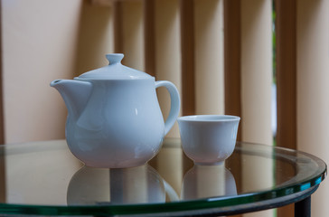 Teapot and teacup on a glass table on the terrace.