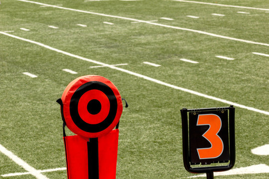 Football field and  orange and black 10 yards chains and 3th down sign 