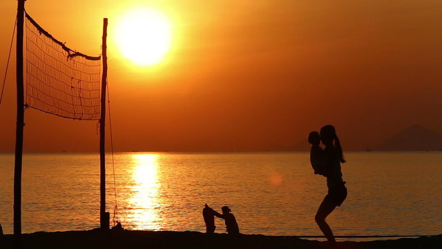 silhouette of mother doing exercises with kid at volleyball net	