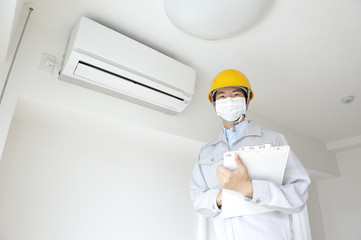 家庭に訪問してエアコンを洗浄する作業員