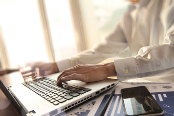 business man hand working on laptop computer on wooden desk as c