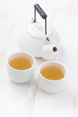 teapot and cups of green tea on a white wooden table