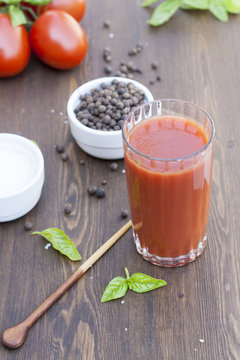 Fresh tomato juice, herbs and spices on wooden table