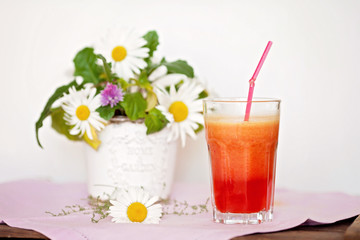 Strawberry, orange and apple fresh in a glass with a lined straw