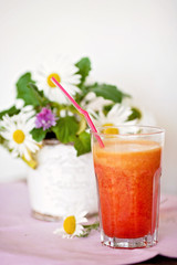 Strawberry, orange and apple fresh in a glass with a lined straw