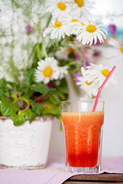 Strawberry, orange and apple fresh in a glass with a lined straw